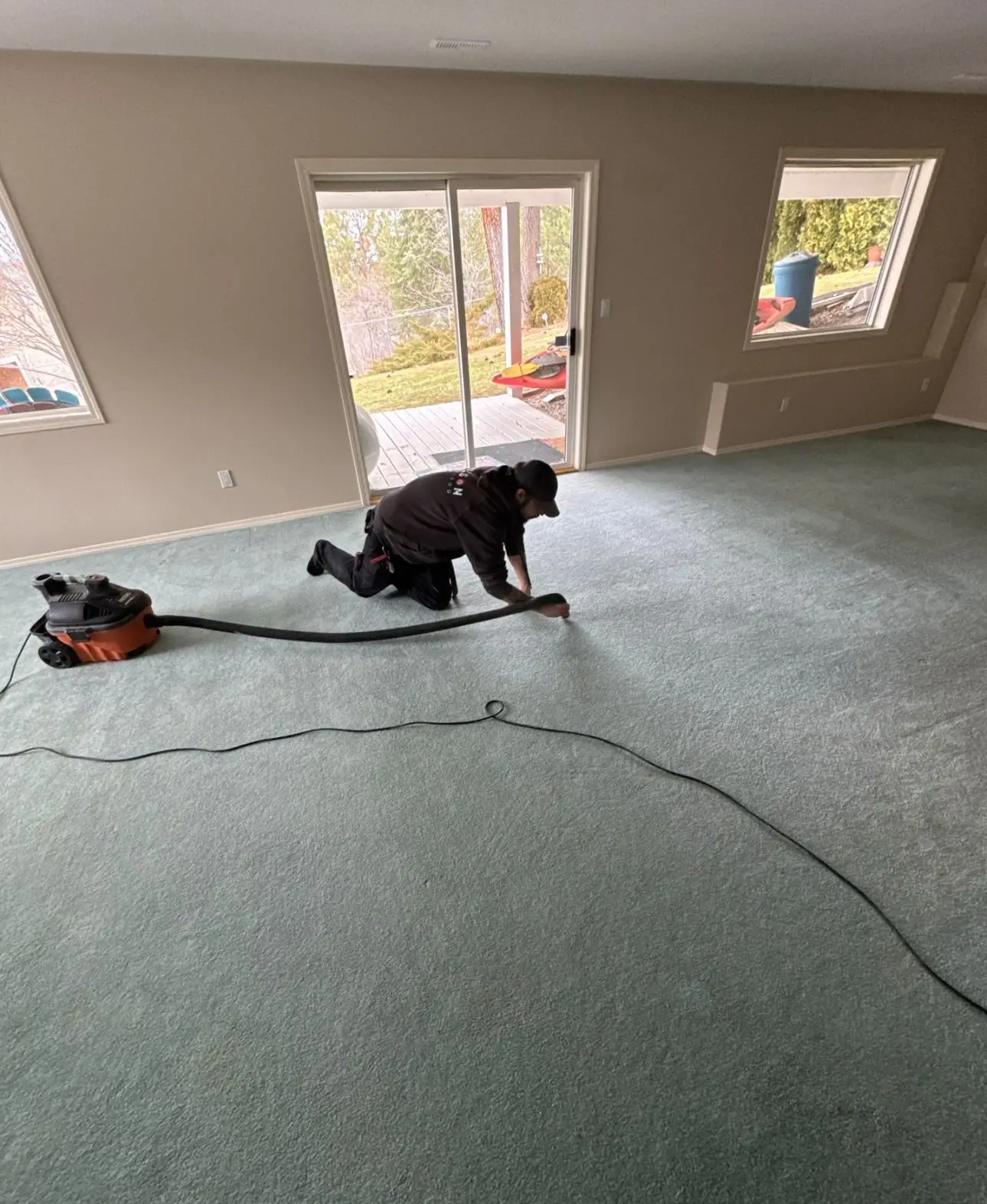 Local Paulson Fire & Flood technician drying carpet inside a Kootenay rental home after water damage