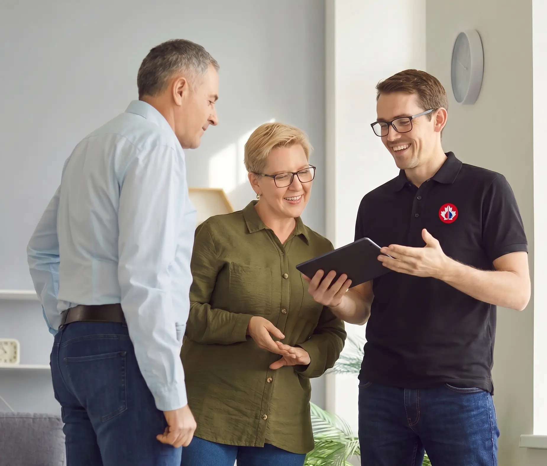 Homeowner couple reviewing restoration details with a technician on a tablet during an insurance claim visit